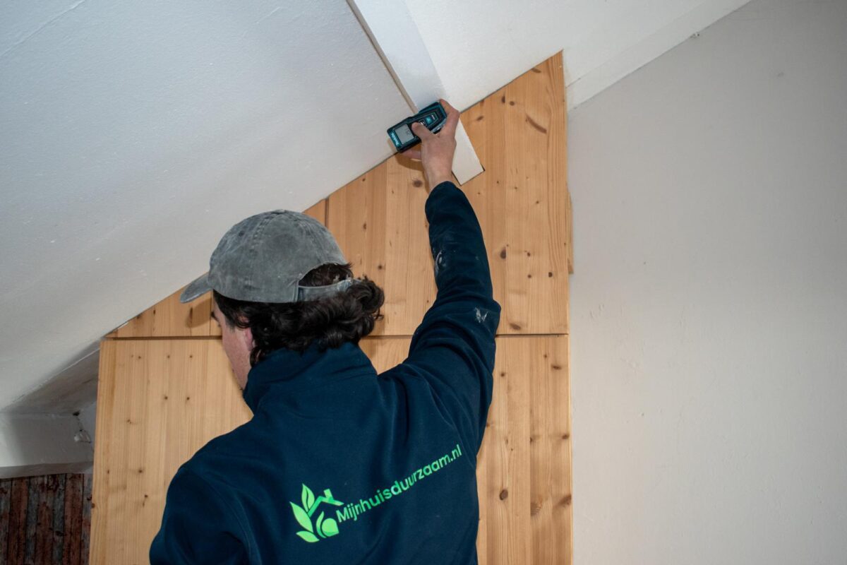 Adviseur meet het dak op voor het toepassen van dakisolatie in een woning.
